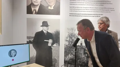 Landesbioschof Christian Kopp spricht mit Karl Nicol, dem Rummelsberger Rektor während der NS-Zeit. Möglich macht das eine eigens entwickelte KI-Station.