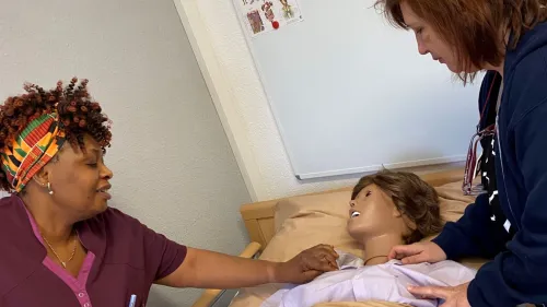 Auszubildende Helen Ubah (links) und Pflegedienstleiterin Lilia Bratkov (rechts) testen die neue Pflegepuppe im Ausbildungszimmer im Stift St. Lorenz. 
